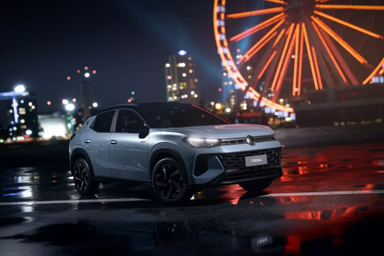 SUV cinza estacionado à noite com uma roda-gigante ao fundo. Luzes da cidade e asfalto molhado.