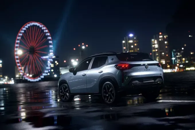 SUV compacto prateado estacionado em pavimento molhado à noite, com uma roda gigante horizonte da cidade