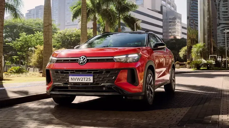 SUV Volkswagen Nivus vermelho estacionado em uma rua da cidade com palmeiras e prédios altos ao fundo.