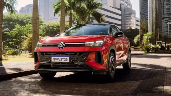 SUV Volkswagen Nivus vermelho estacionado em uma rua da cidade com palmeiras e prédios altos ao fundo.