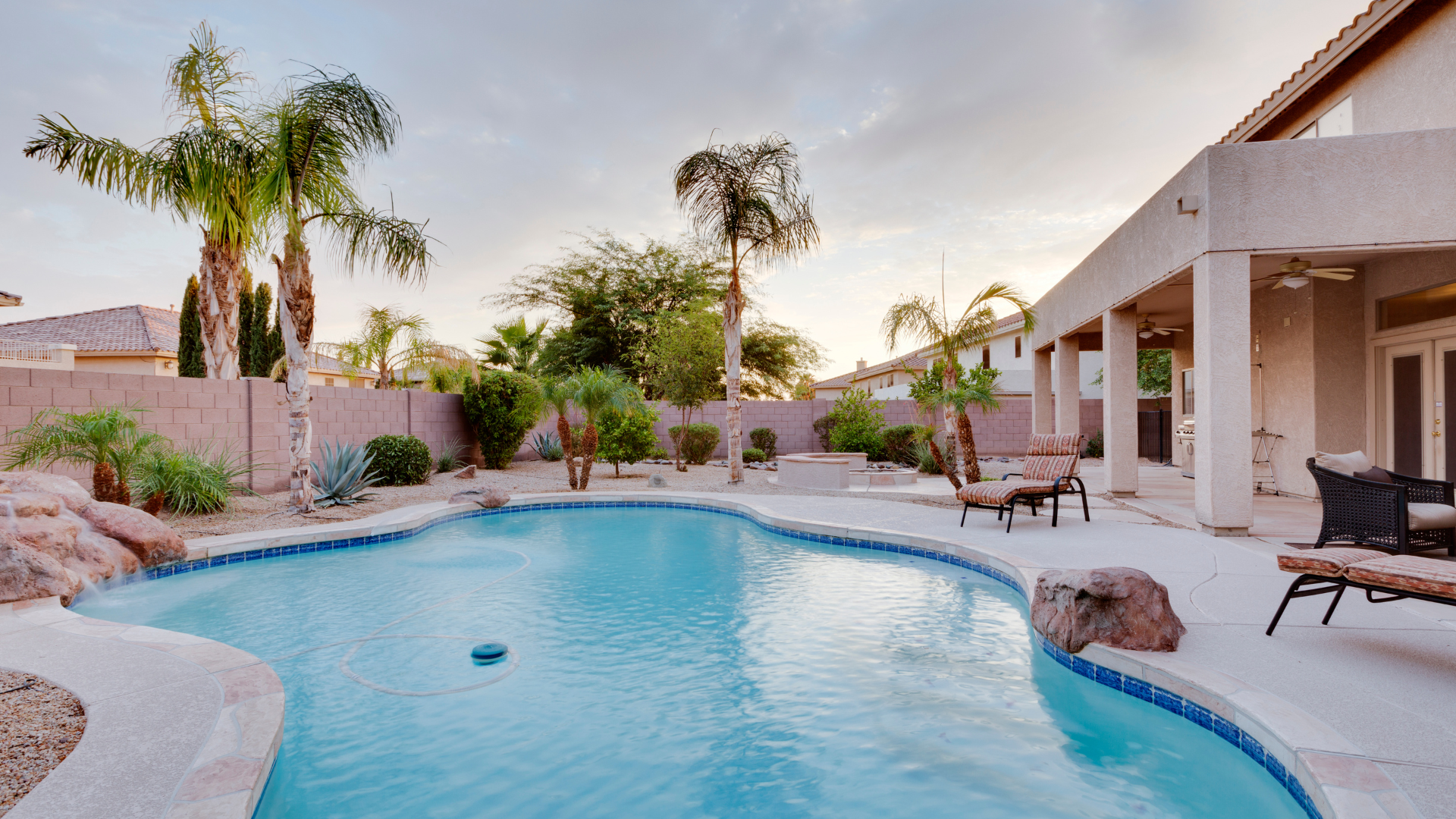 There is a large swimming pool in the backyard of a house.