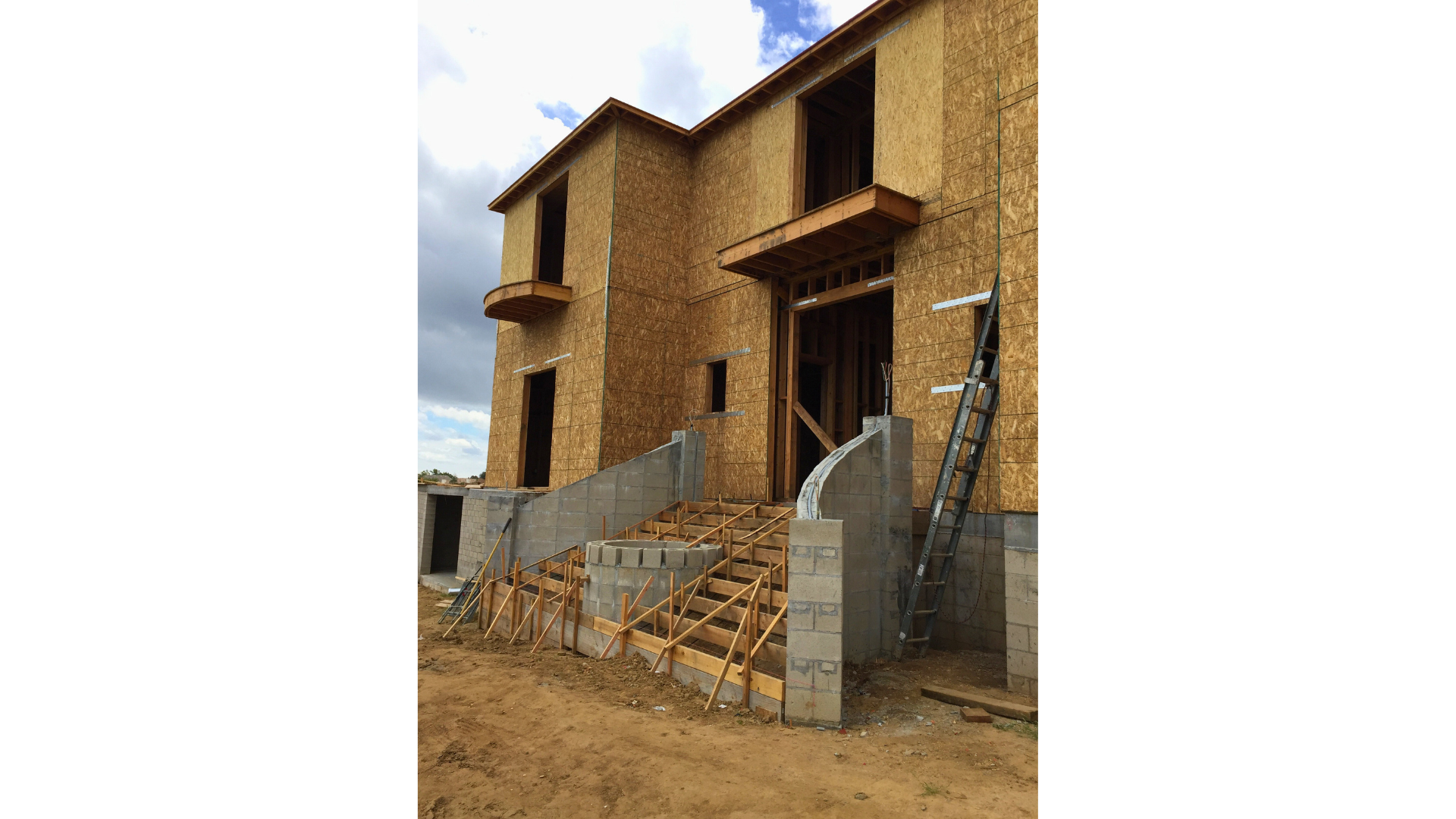 A large house under construction with stairs leading up to it.