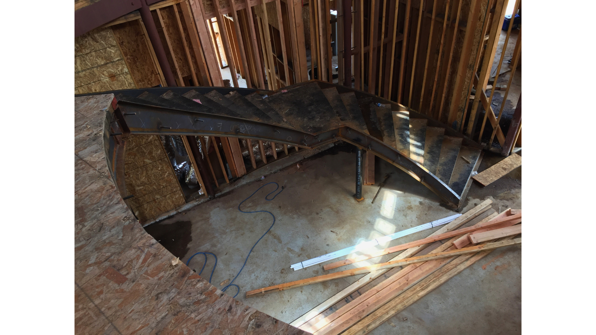 A spiral staircase is being built in a house under construction.