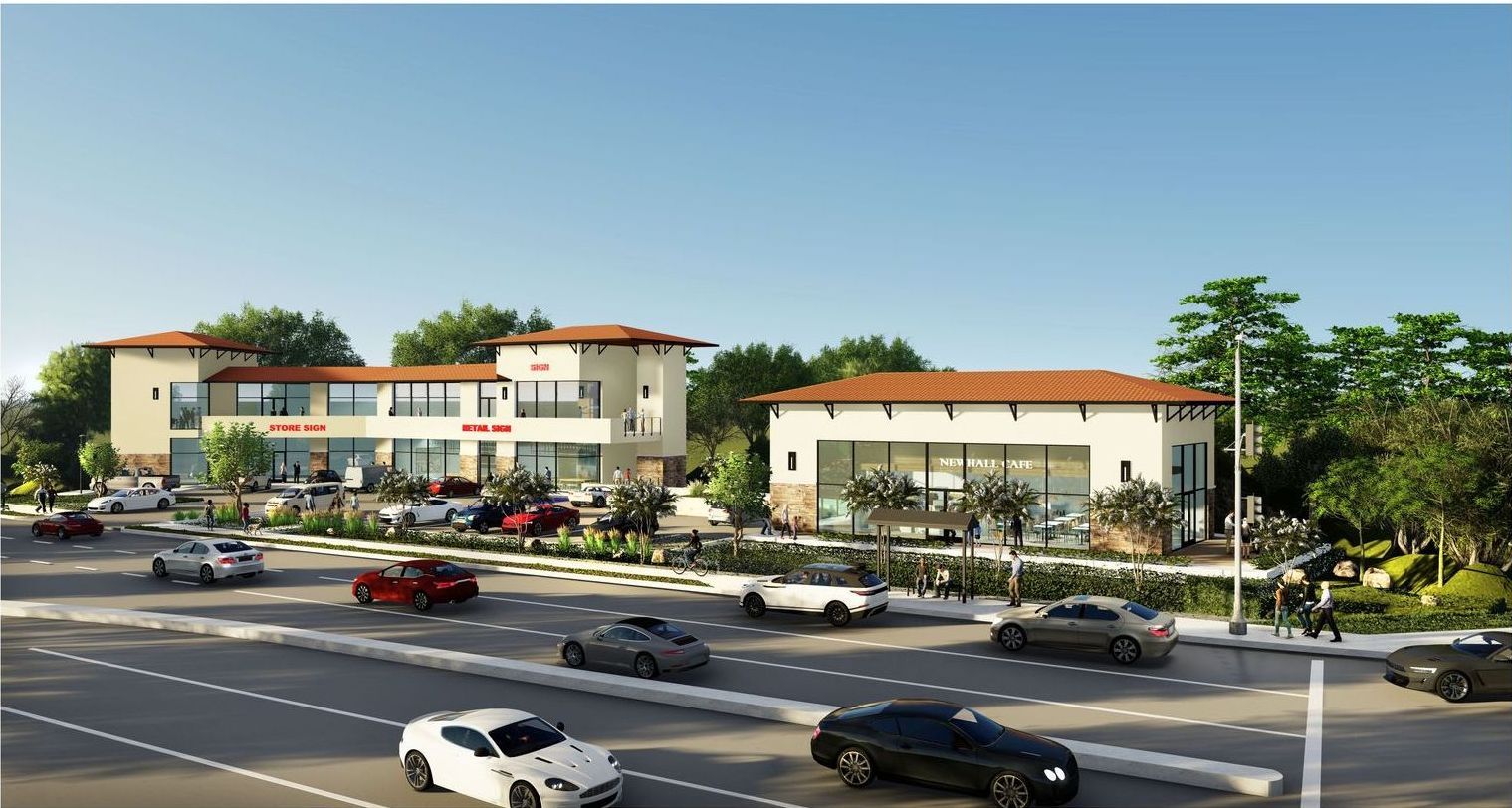A group of cars are driving down a street in front of a building.