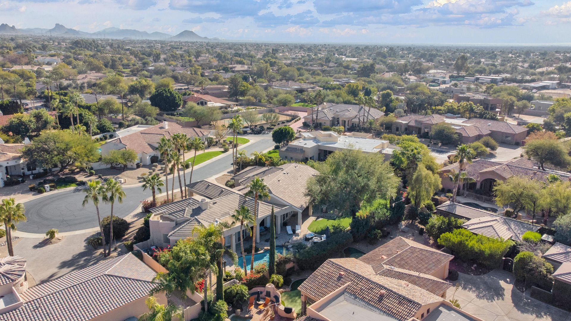 An aerial view of a residential area with lots of houses and palm trees.