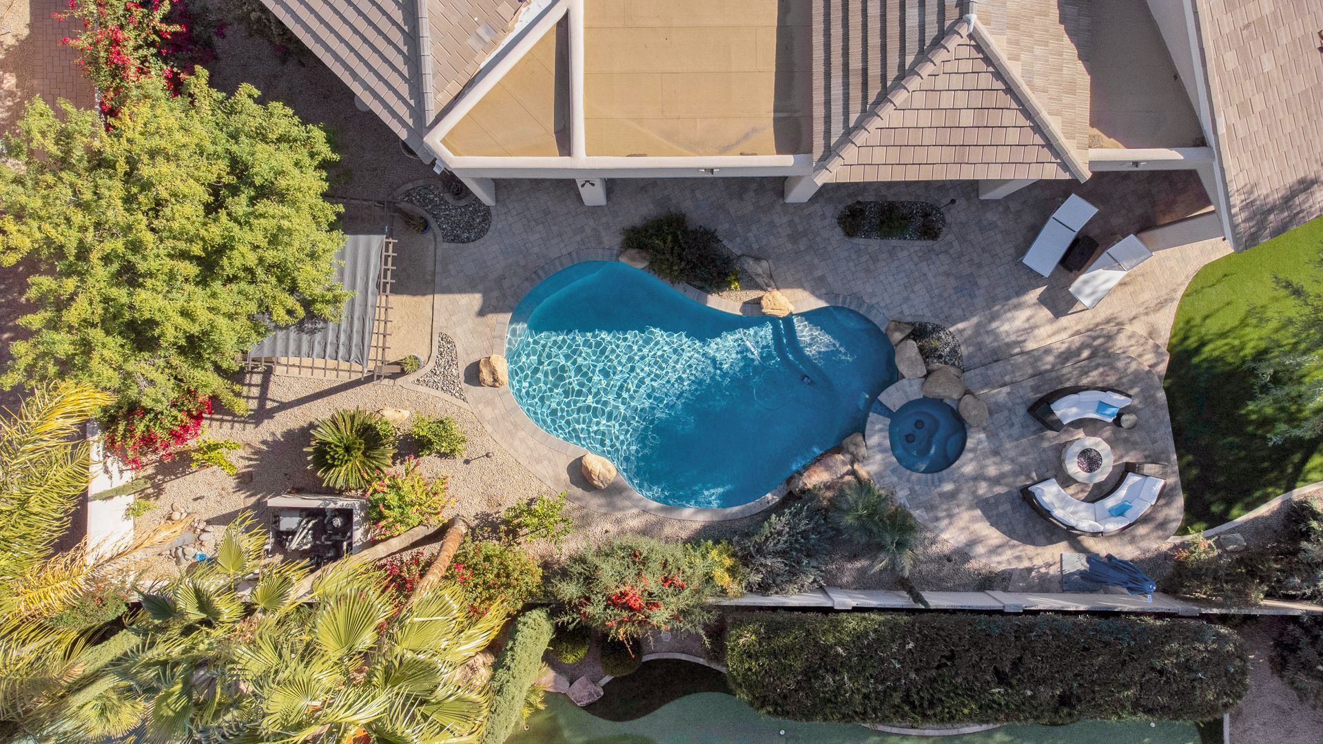 An aerial view of a house with a large swimming pool in the backyard.