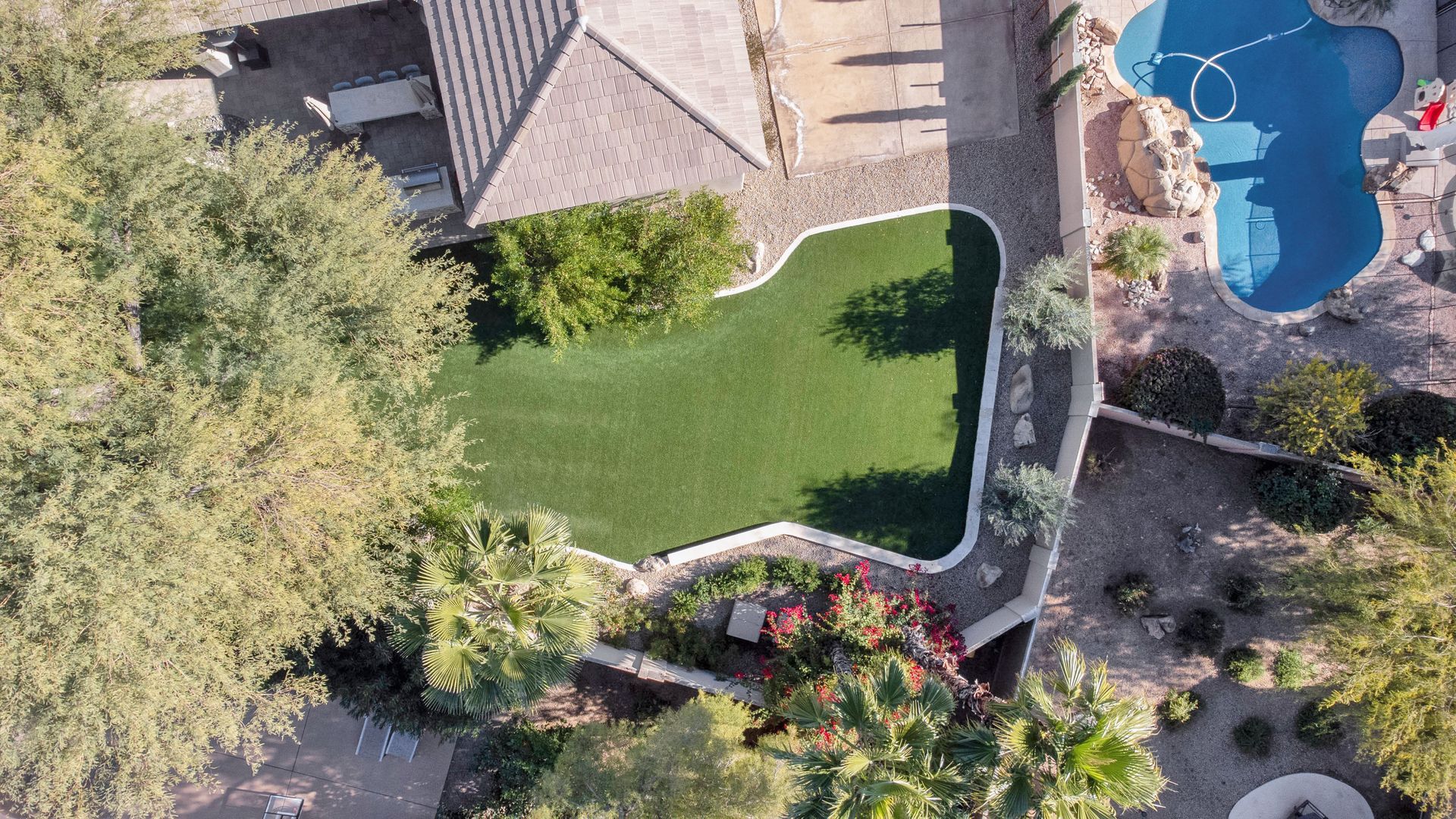An aerial view of a house with a large lawn and a pool.