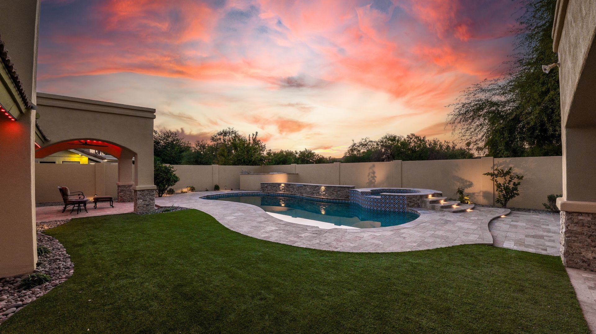 A large swimming pool in the backyard of a house at sunset.