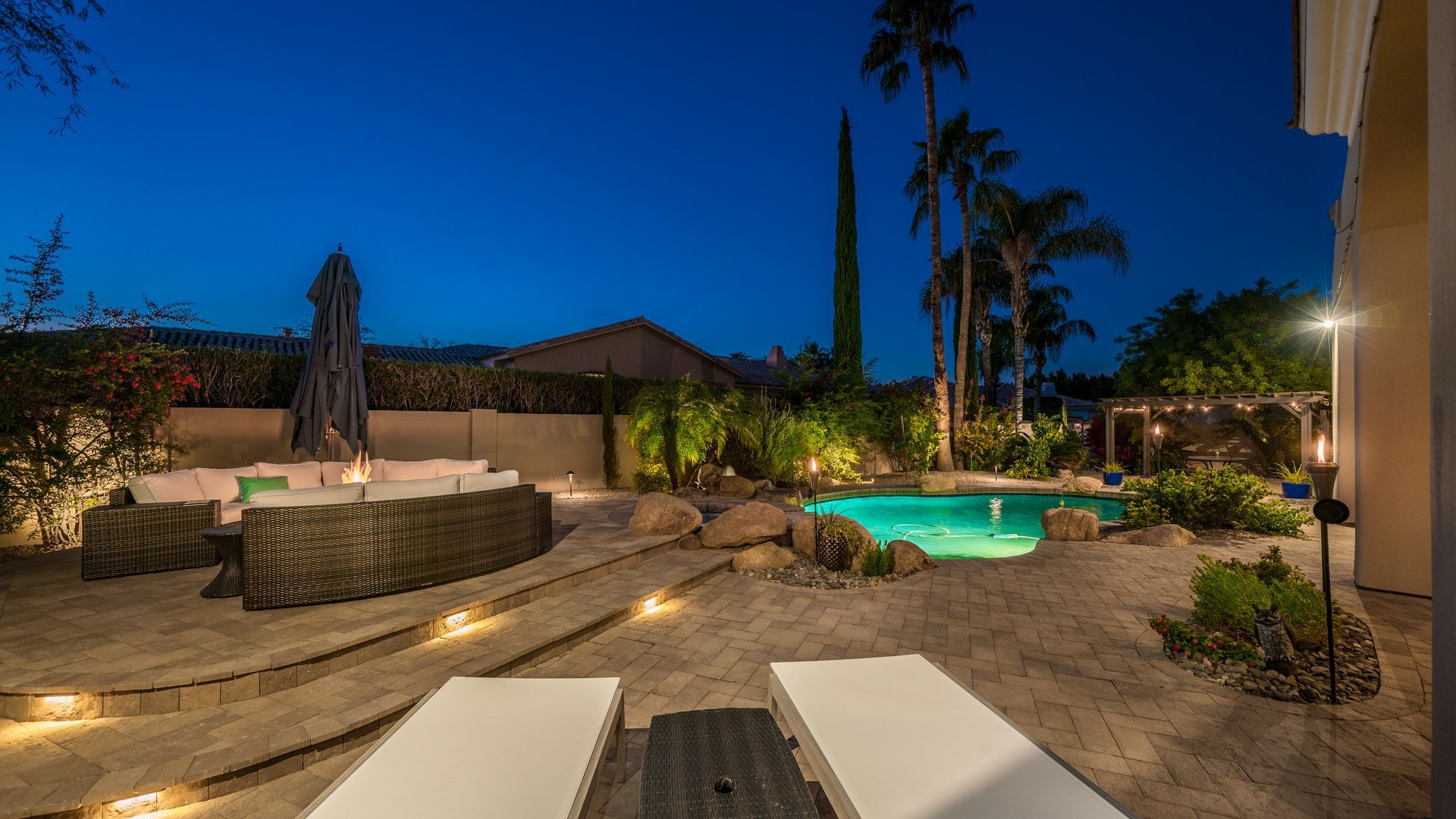 A large swimming pool in the backyard of a house at night.