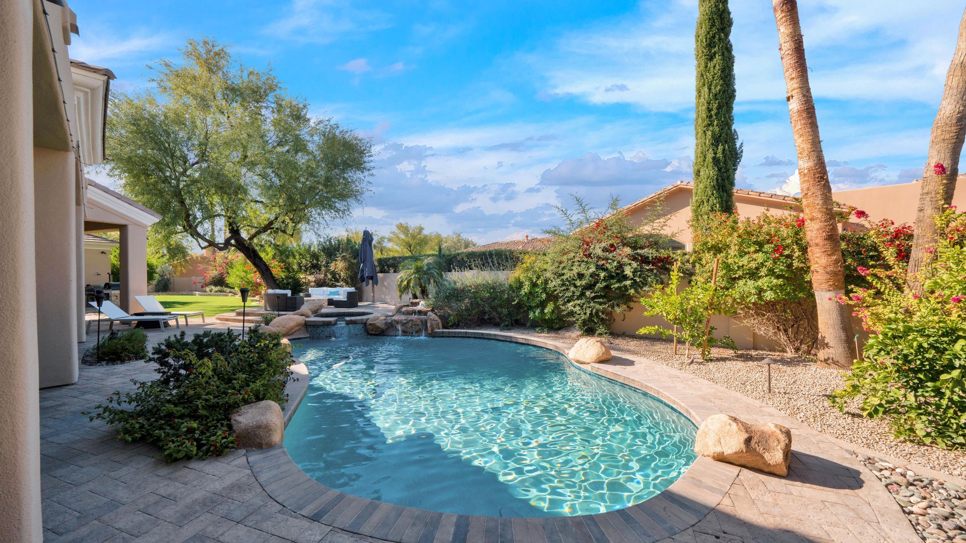 There is a large swimming pool in the backyard of a house.