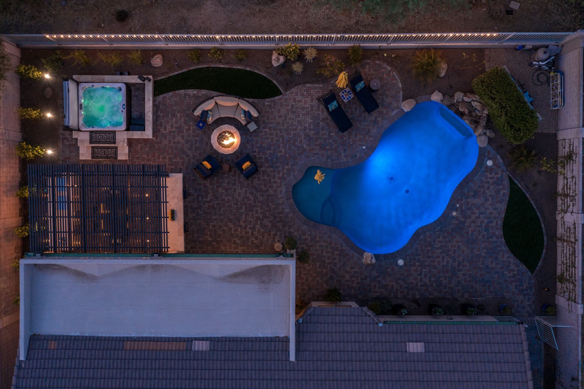 An aerial view of a backyard with a large blue pool and a fire pit.