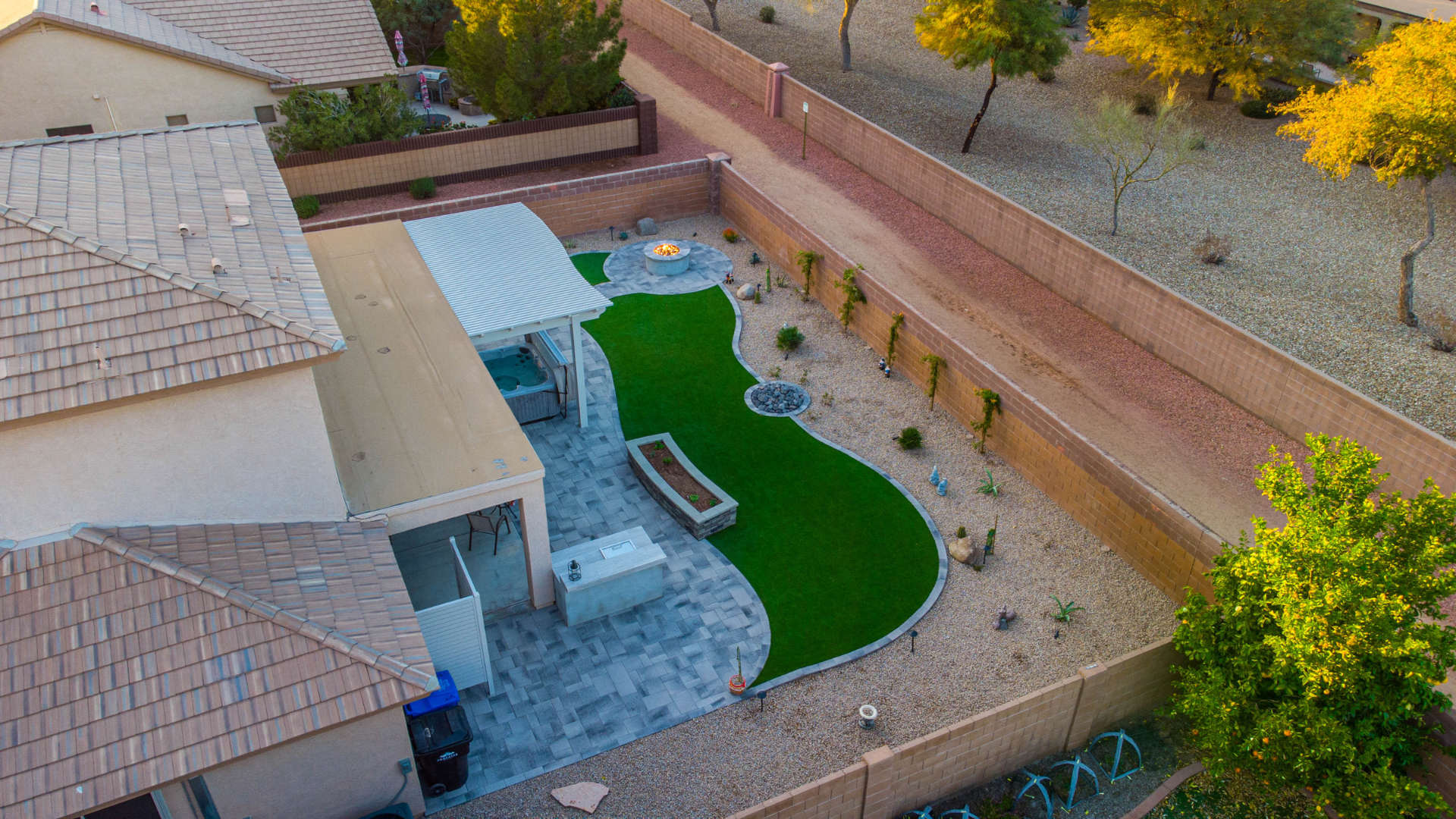 An aerial view of a backyard with a lush green lawn and a fire pit.