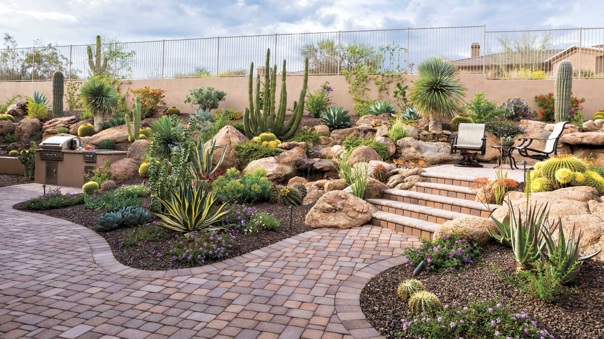 A patio with a brick walkway and stairs surrounded by rocks and plants.