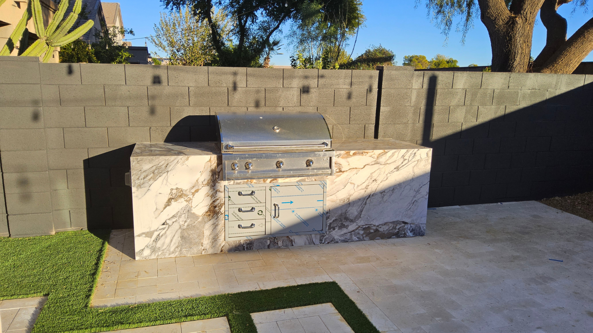 A grill is sitting on top of a concrete counter in a backyard.