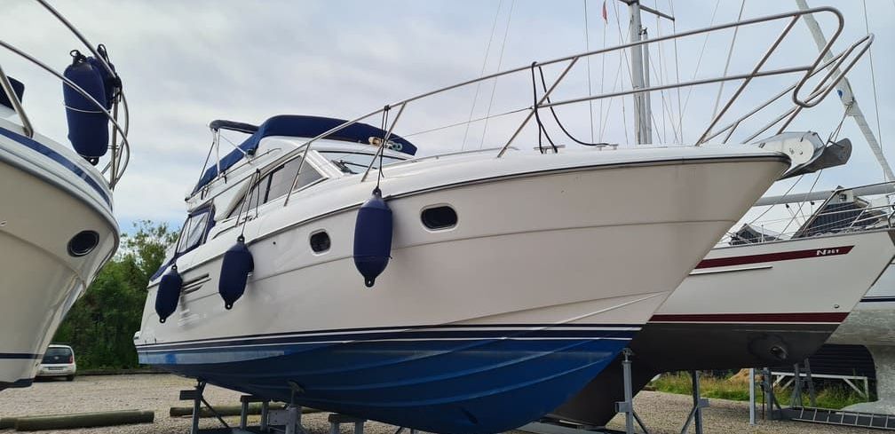 A white boat is parked next to another boat in a marina.