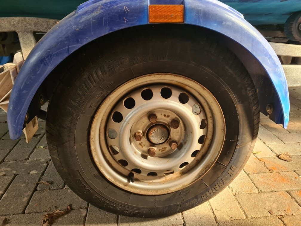A close up of a tire on a trailer with a blue fender