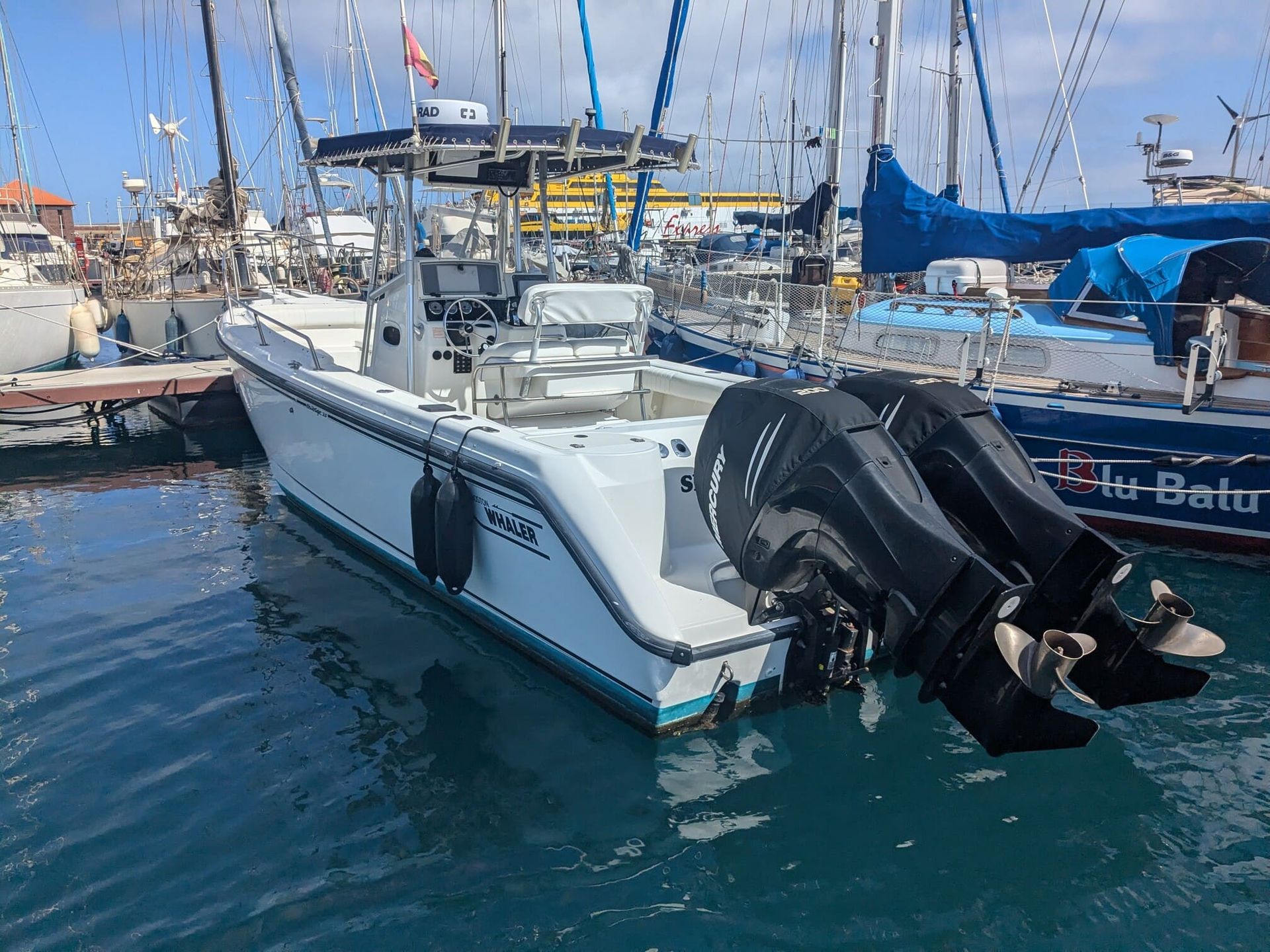 A boat with two engines is docked in a marina.