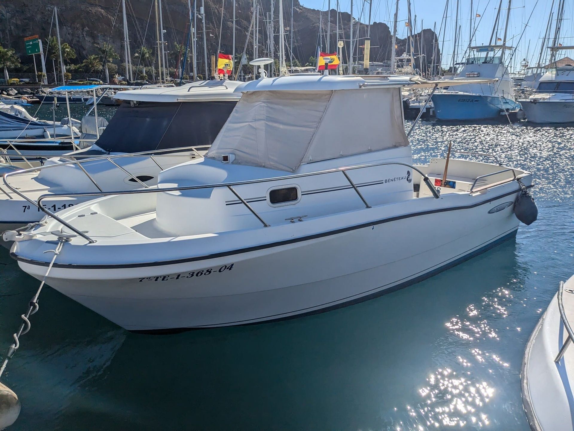 A white boat is docked in a marina surrounded by other boats.