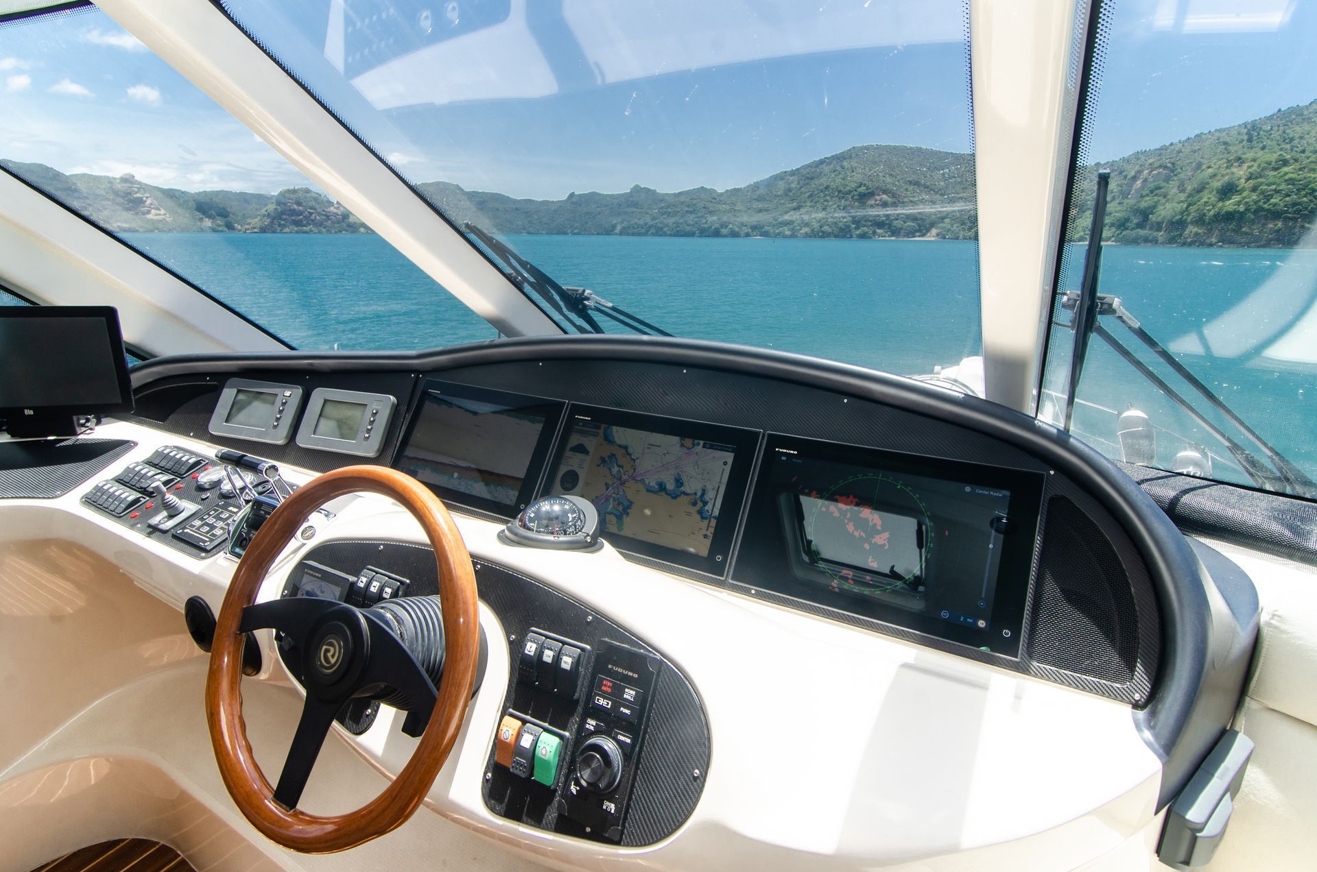 The dashboard of a yacht with a wooden steering wheel