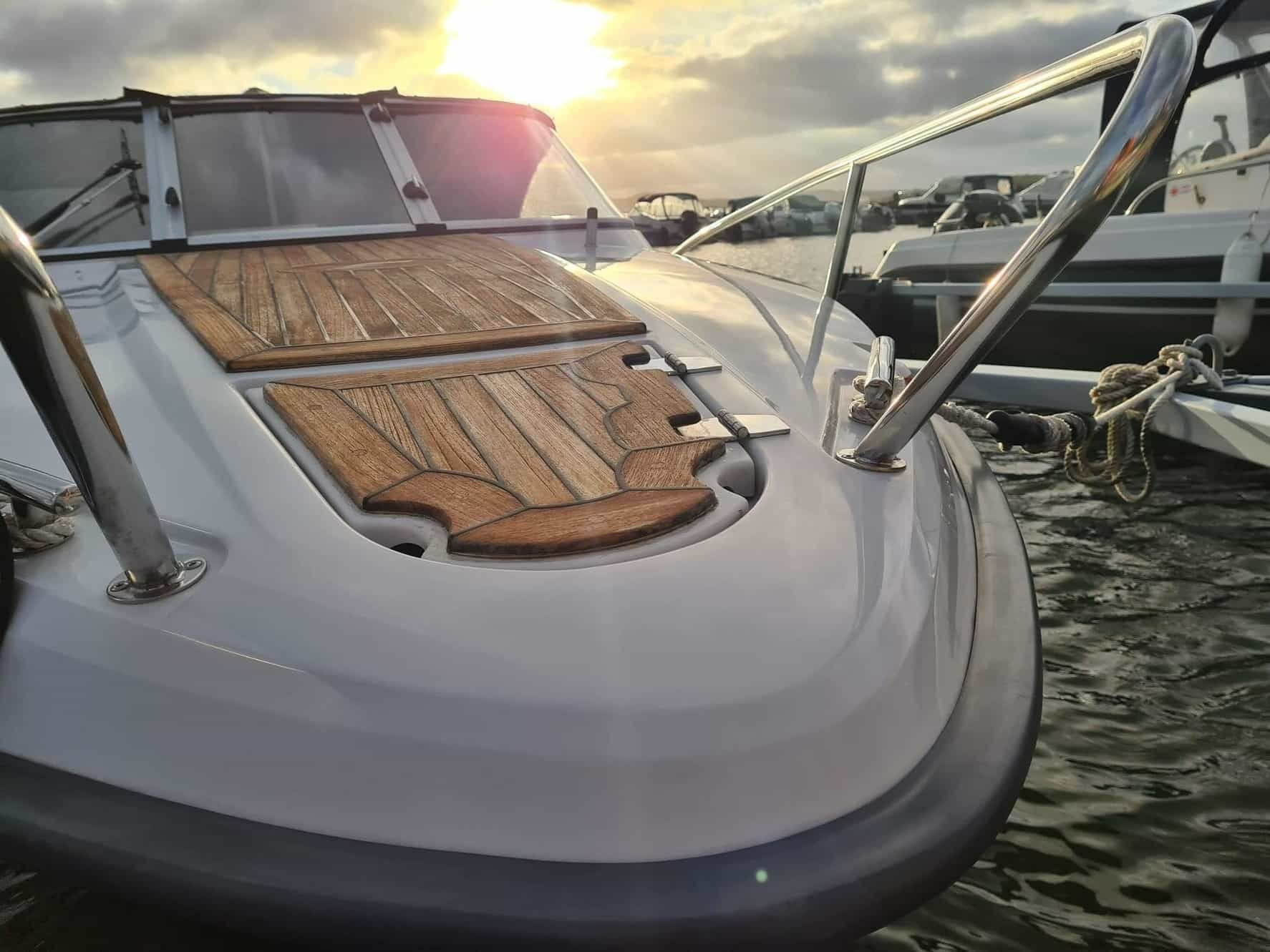 A white boat with a wooden deck is docked in the water.