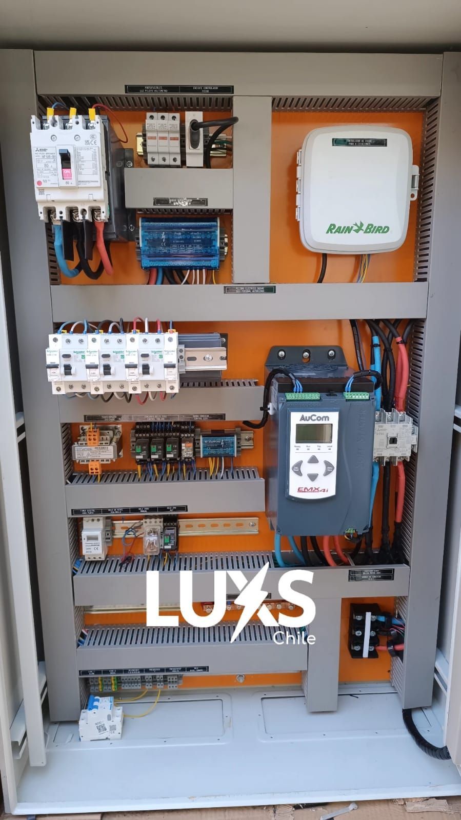 Una caja blanca con muchas válvulas encima está sobre un campo de tierra.