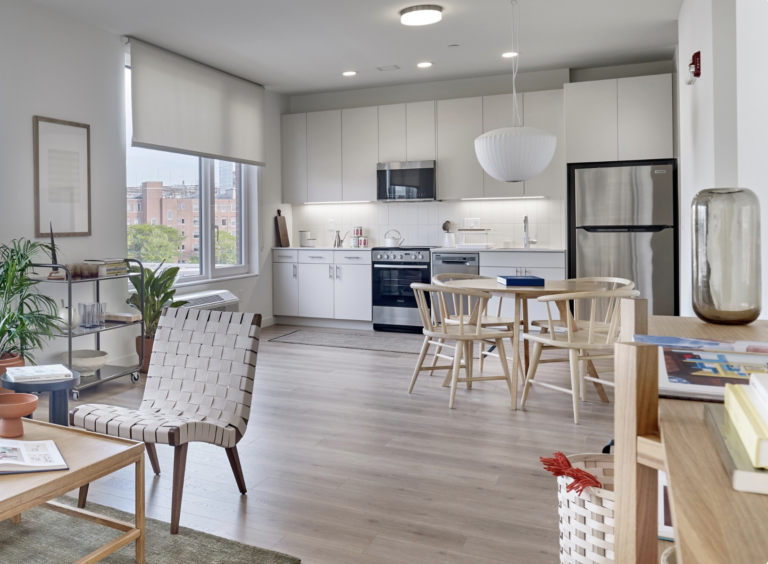 Bright, modern apartment interior with open kitchen and dining area; light wood floors and neutral decor.