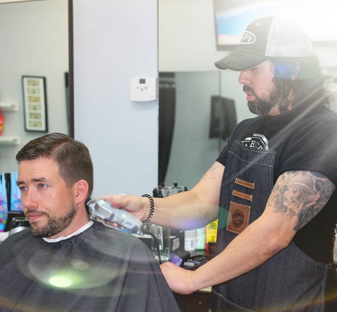 Barber trimming a client’s hair in a salon chair, with a mirror and clippers visible.