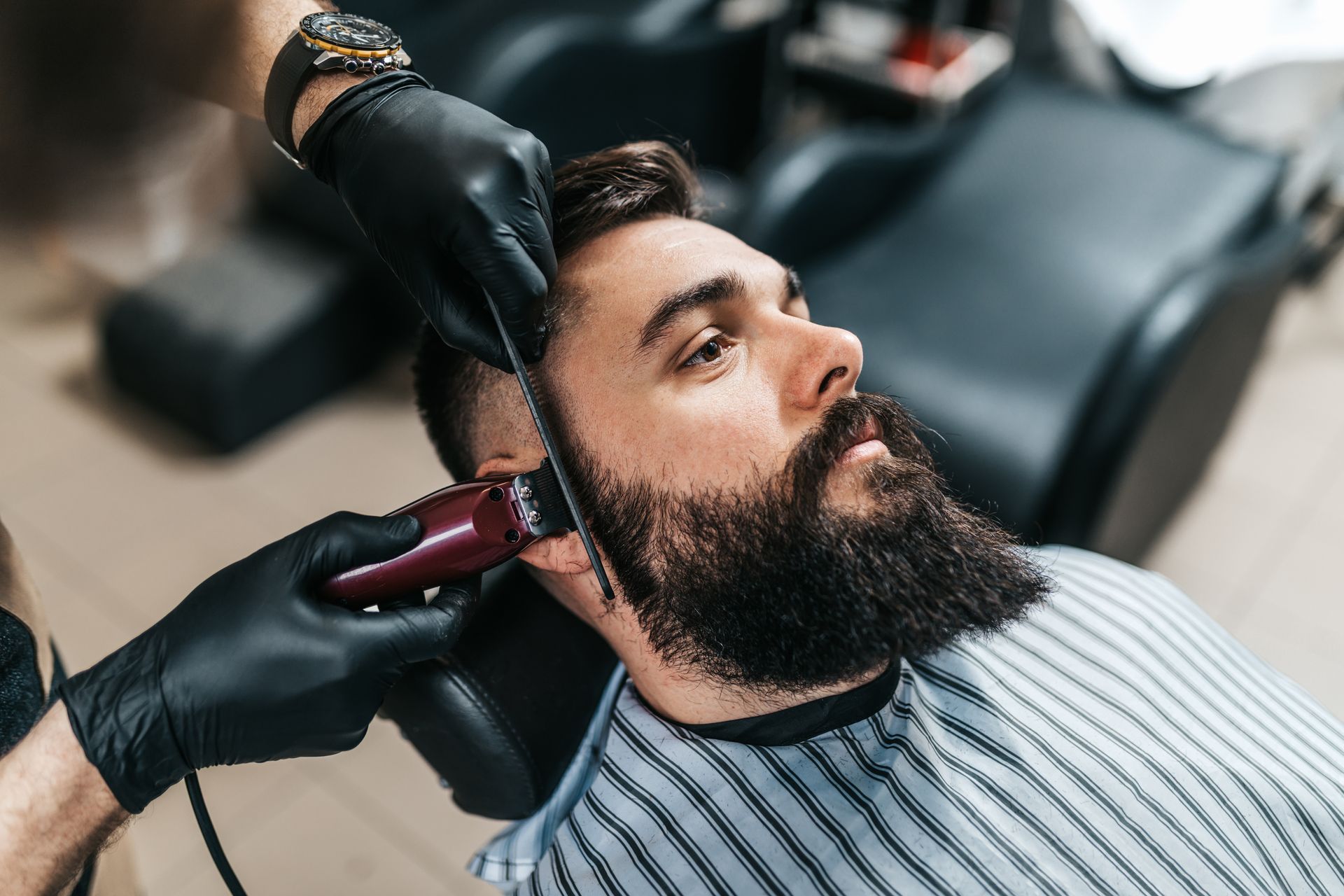 Bearded man getting a haircut with electric clippers in a barbershop