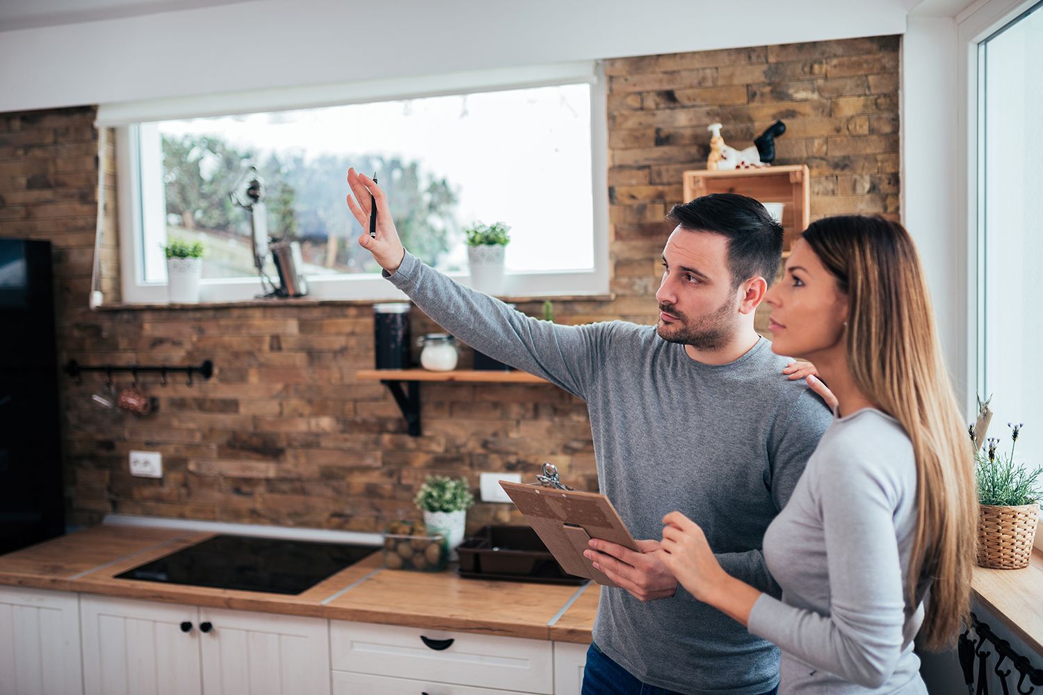 Two people reviewing a tablet while looking around a modern kitchen.