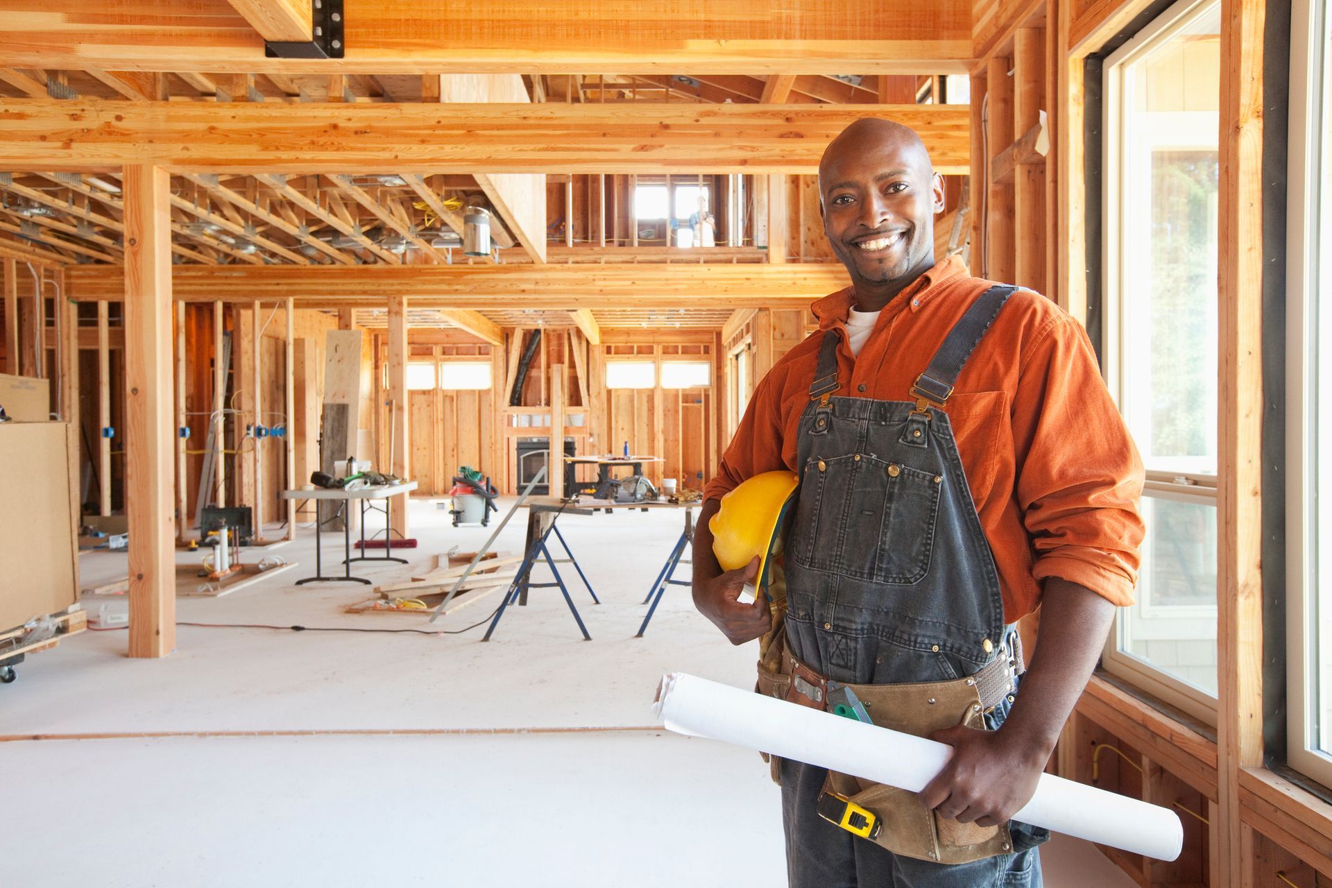 A man is holding blueprints in an unfinished room.