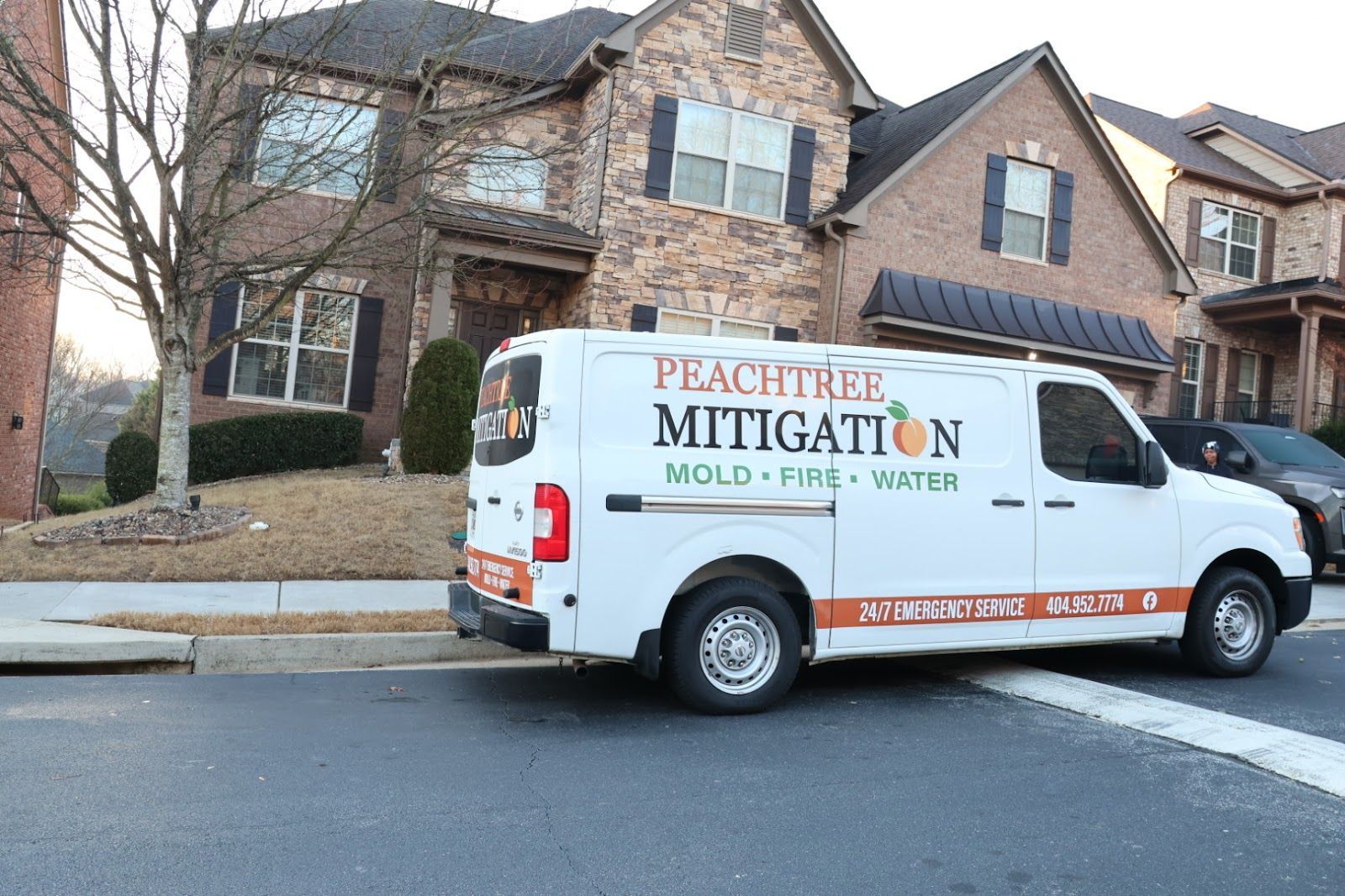 White Peachtree Mitigation van parked on a residential street in front of brick houses.