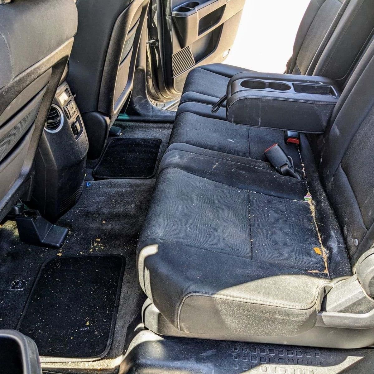 The back seat of a car is dirty and needs to be cleaned