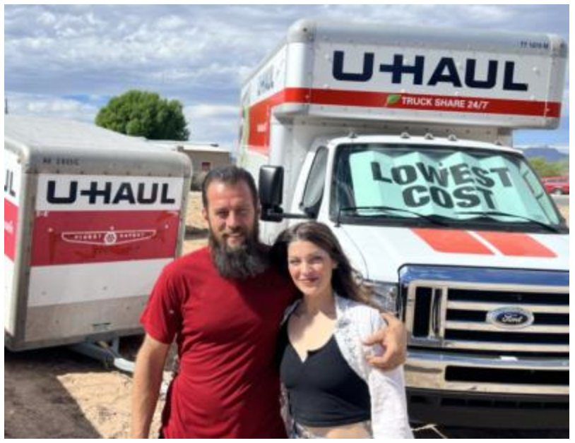 A man wearing a graduation sash is sitting on a ledge next to a fountain.