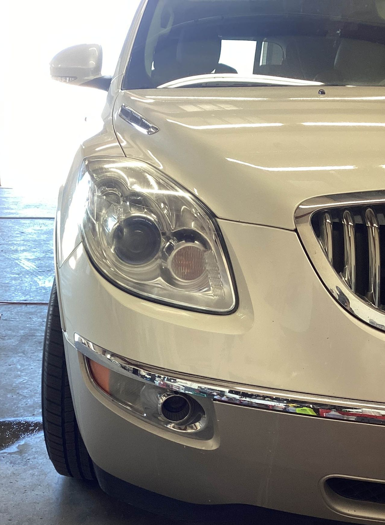 Tan Buick SUV, front view, showing headlight and chrome trim.