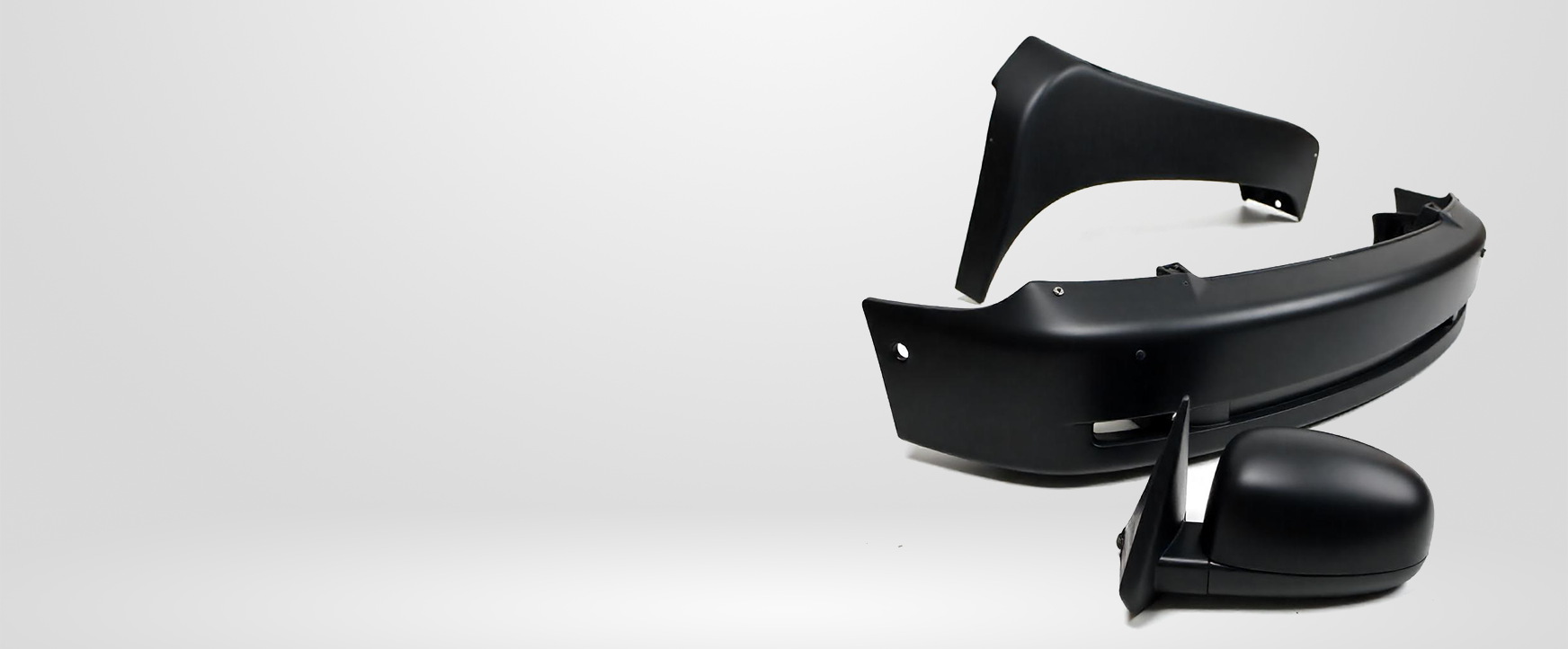 Black car parts arranged on a light gray gradient background. Includes bumper, trim, and side mirror.