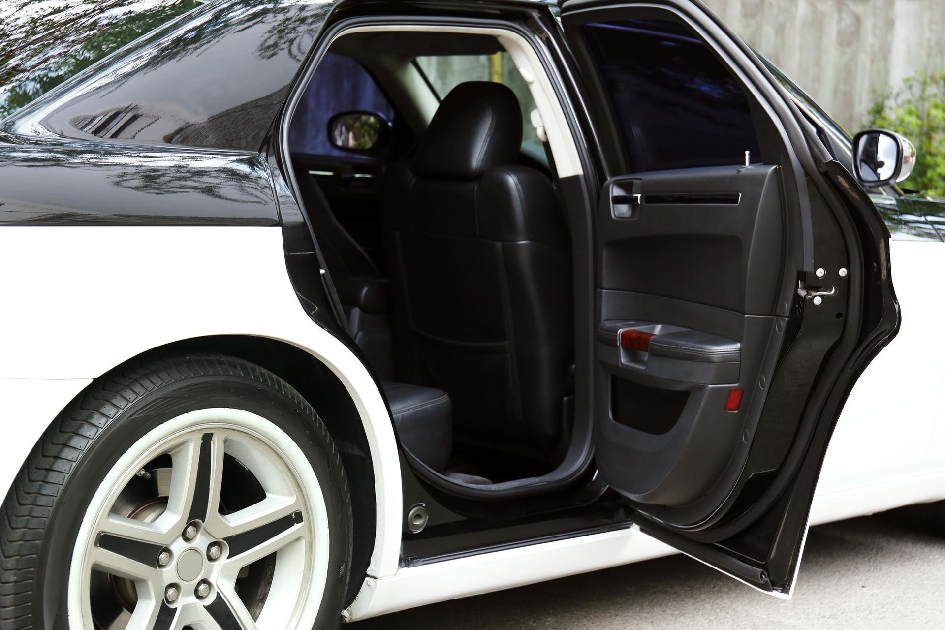 White and black car with open rear door, revealing black interior.