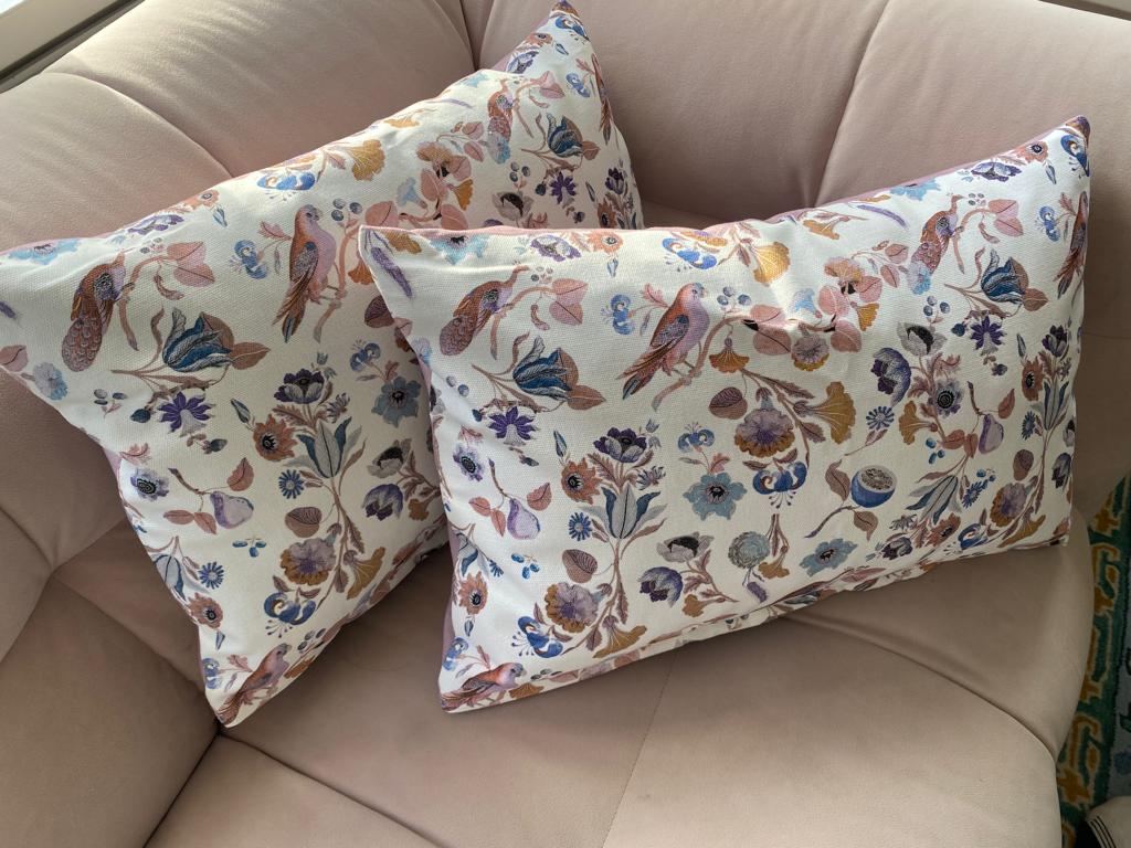 Twee bloemenkussens liggen op een roze bank