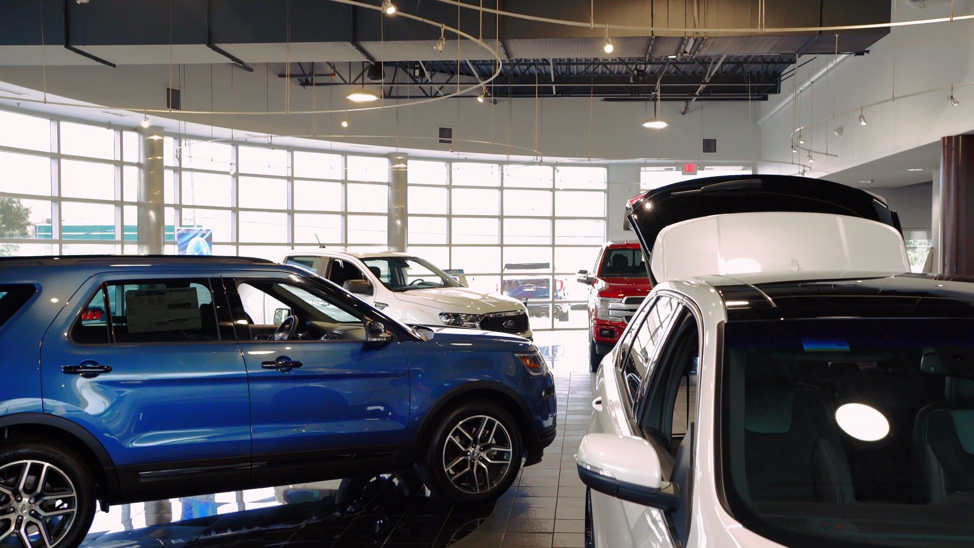 A row of cars are parked in a showroom.