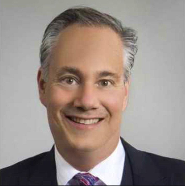 A man in a suit and tie is smiling for the camera.