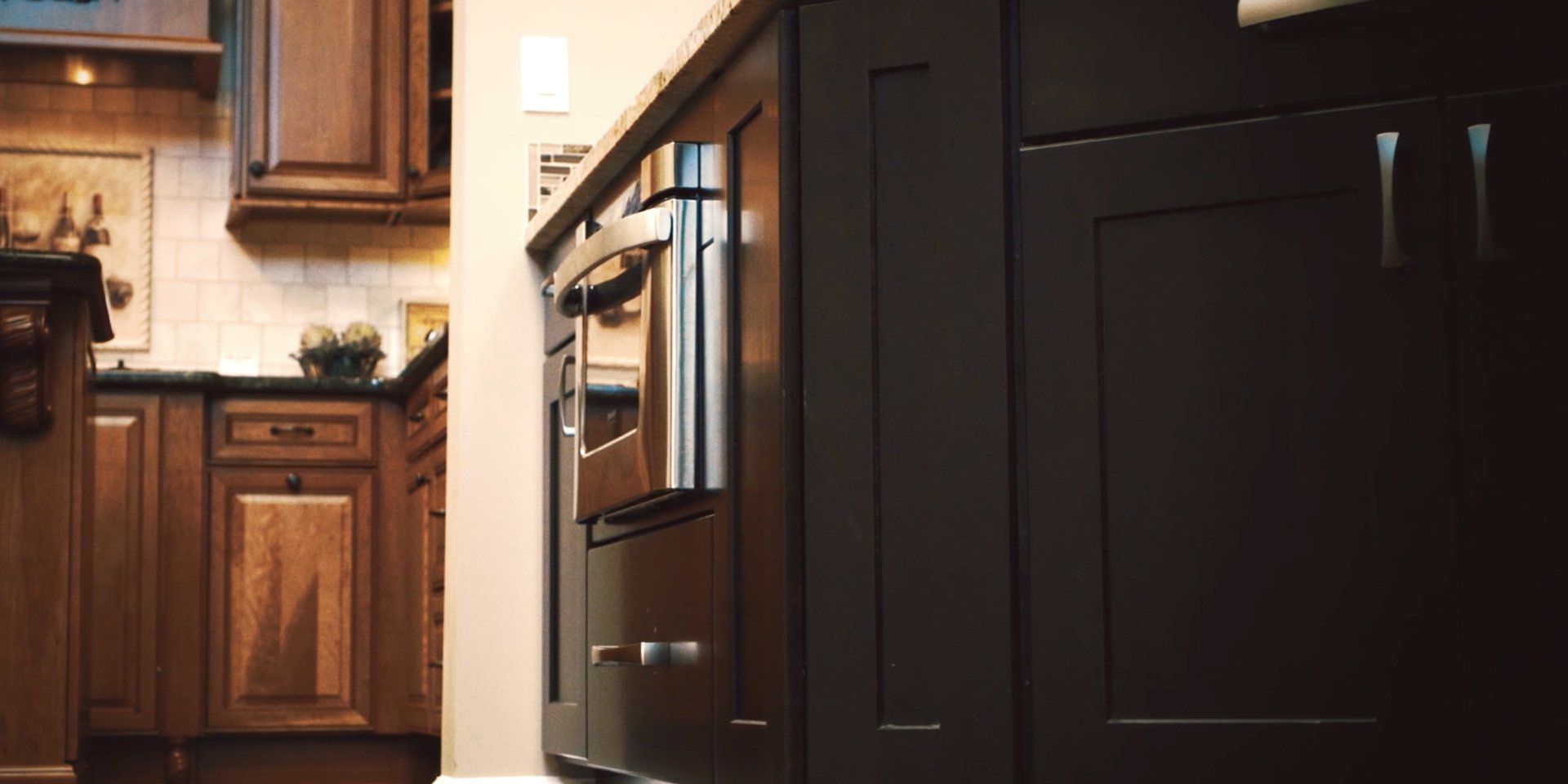 A kitchen with black cabinets and wooden cabinets and a stove.