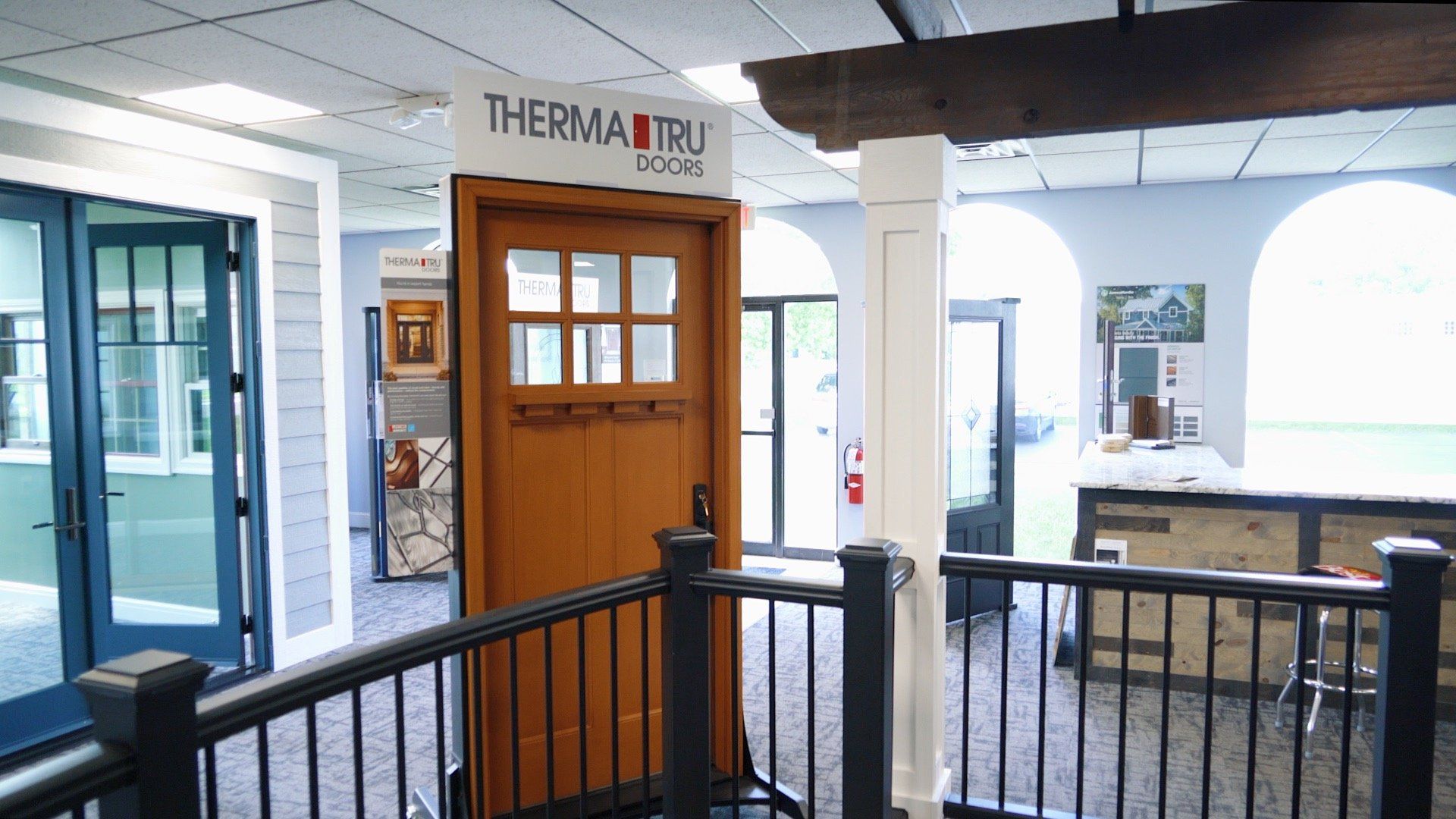 A showroom with a wooden door and a black railing.
