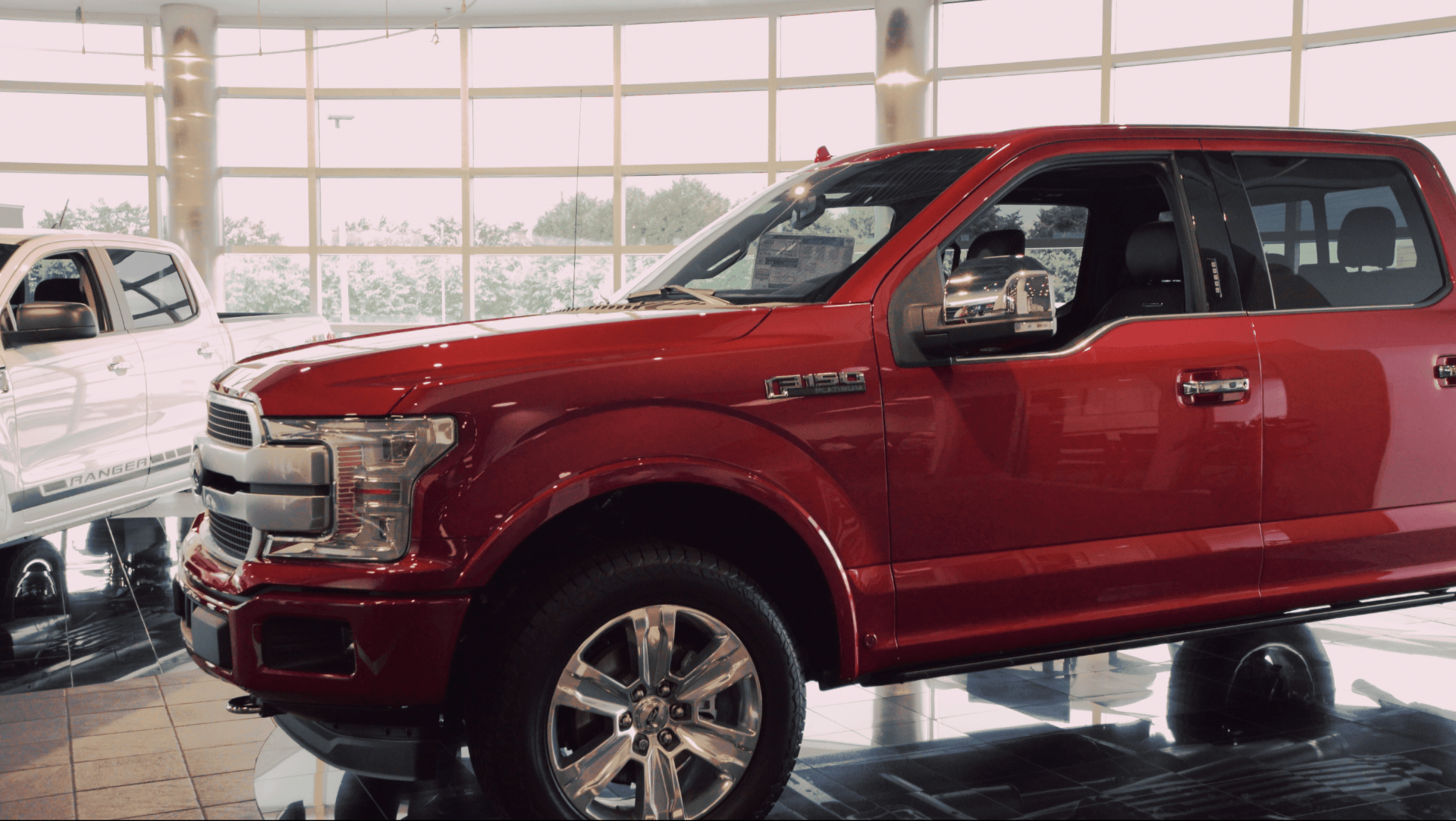A red ford f150 truck is parked in a showroom.