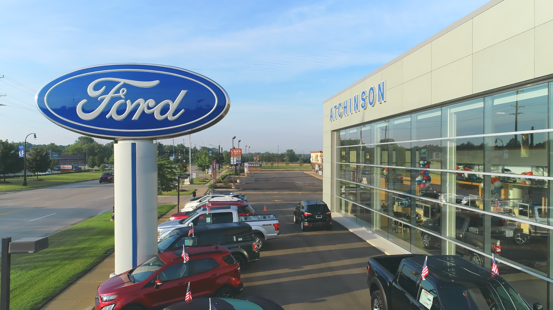 An aerial view of a ford dealership with cars parked in front of it.