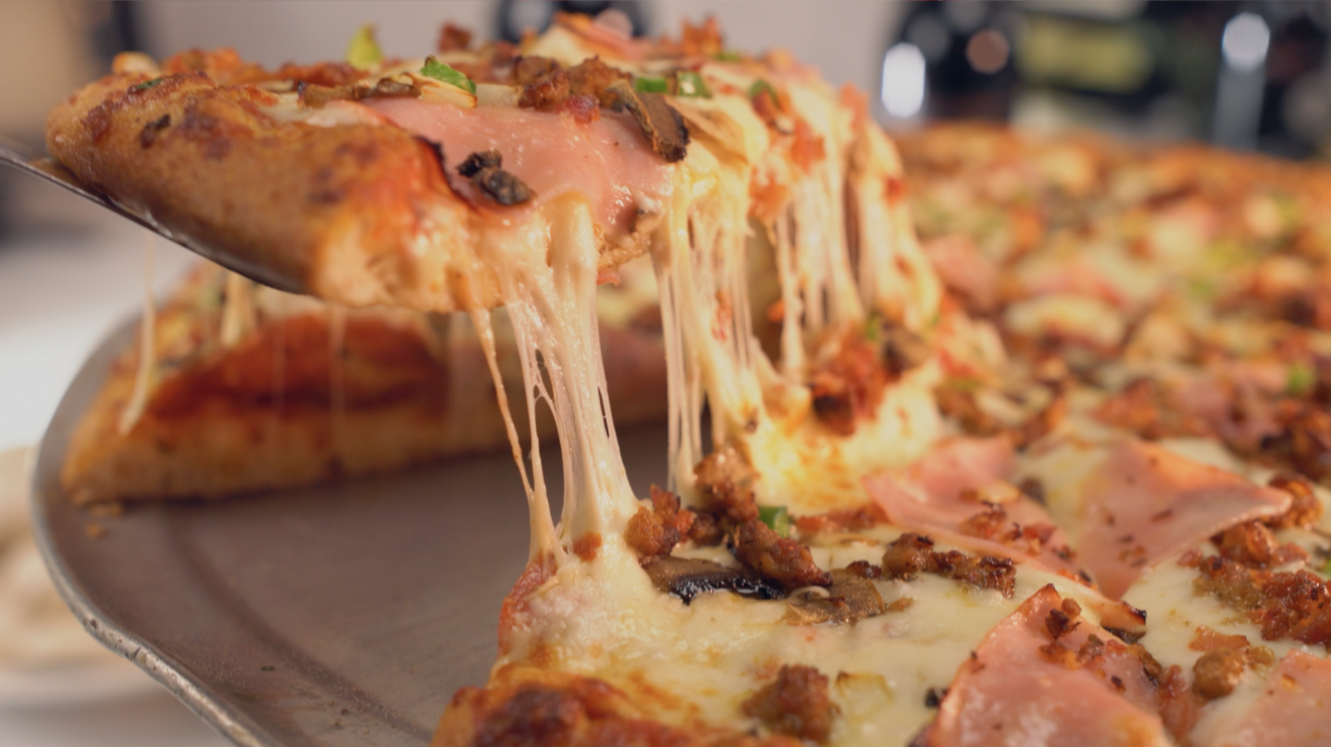A slice of pizza is being taken out of a pizza on a pan.