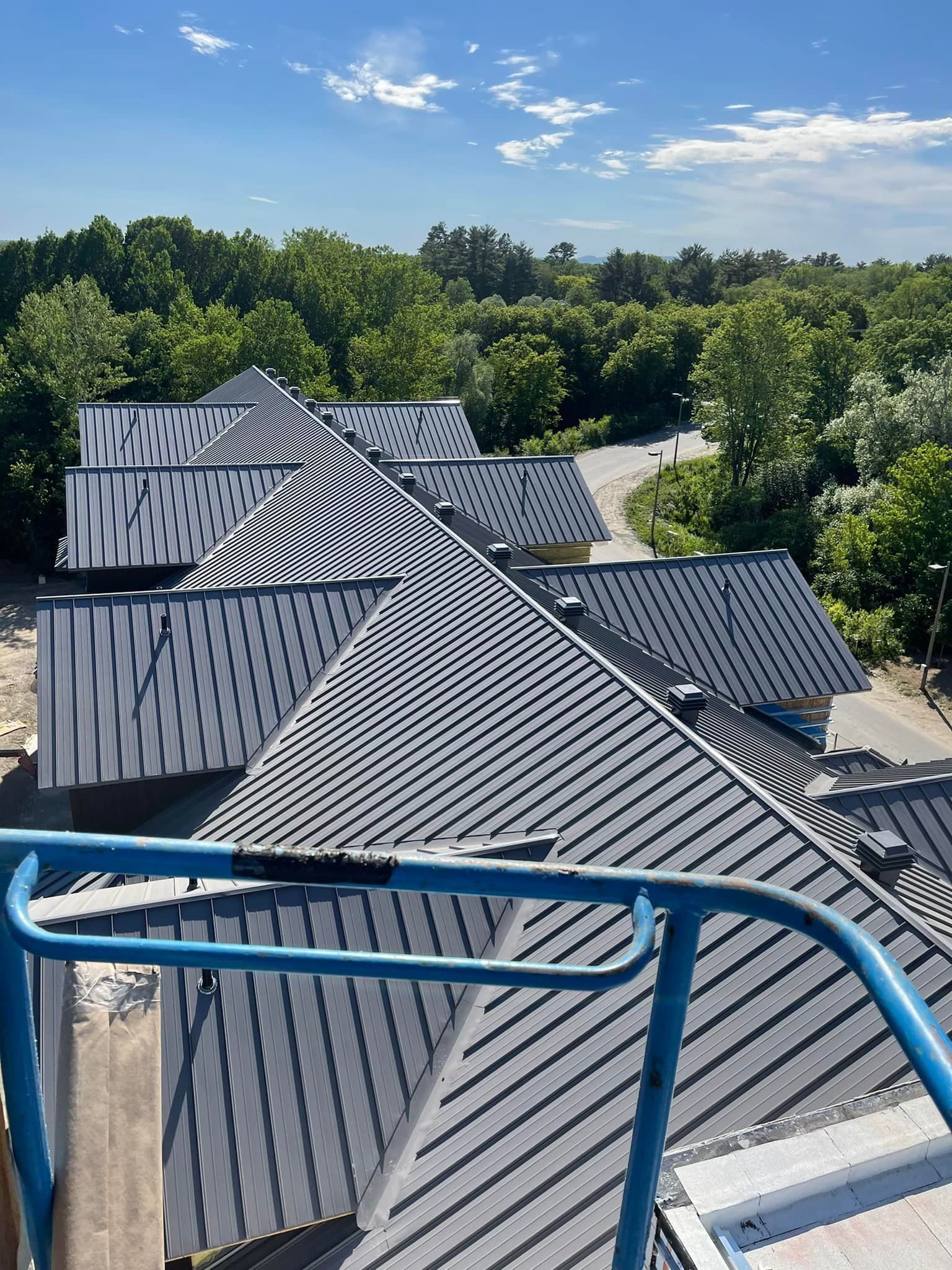 Une vue aérienne d'un toit avec une balustrade bleue et des arbres en arrière-plan.