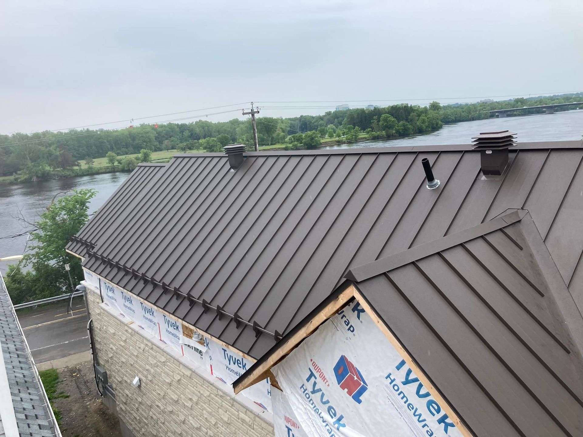 Un toit en métal brun est en cours d'installation sur une maison.