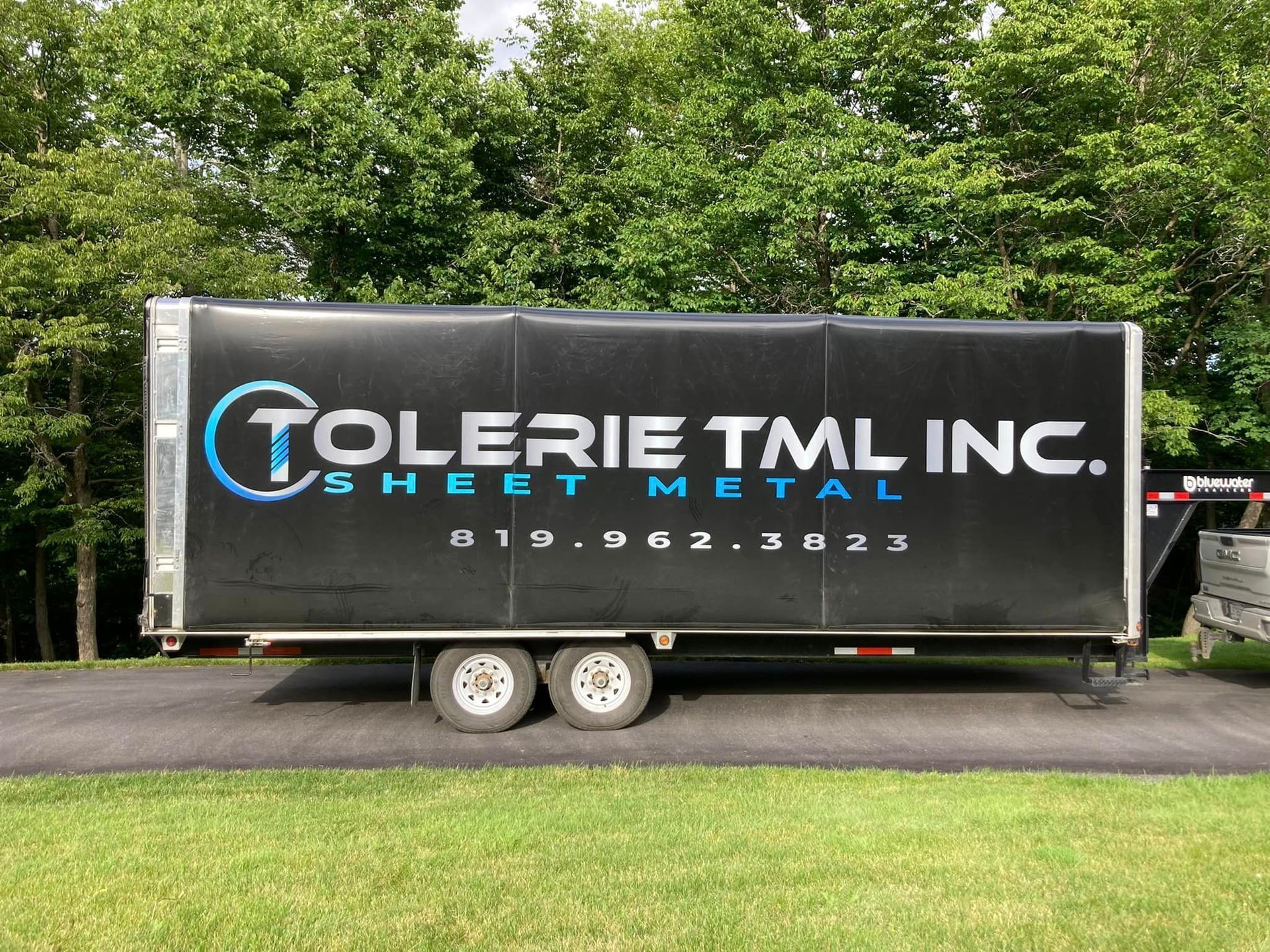 Une remorque en tôle de la société tolerie tml inc. est stationnée sur le bord de la route.