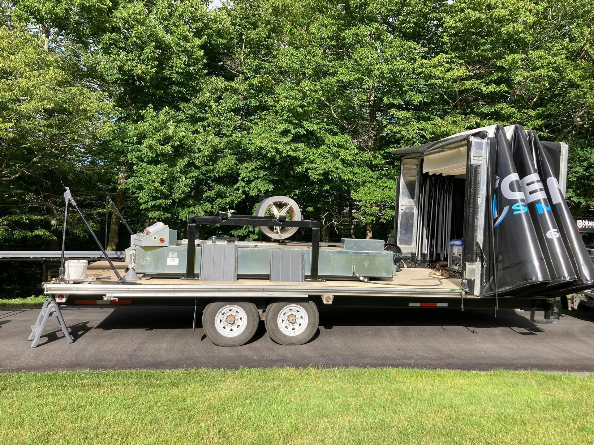 Une remorque avec la porte ouverte est garée dans un champ herbeux.