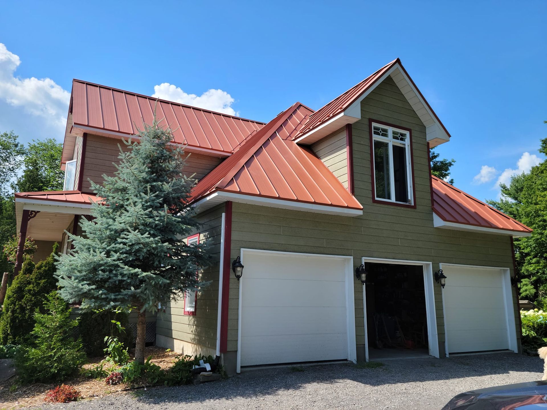 Une maison avec un toit rouge et des portes de garage blanches