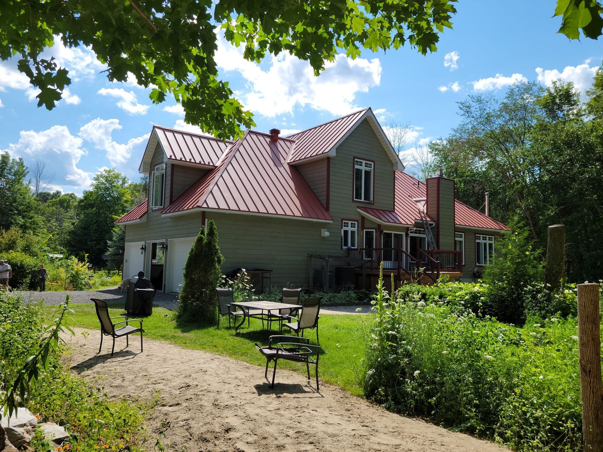 Une grande maison au toit rouge se trouve au milieu d'un champ verdoyant.